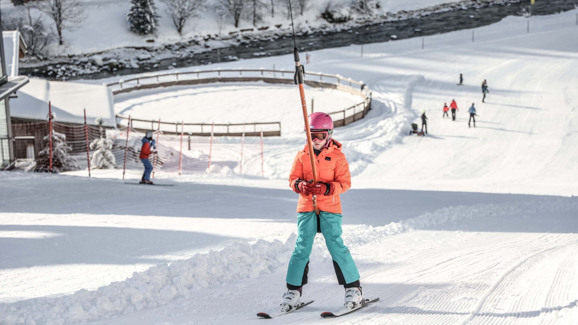 Skifahrende Person in orangefarbener Jacke im Schnee