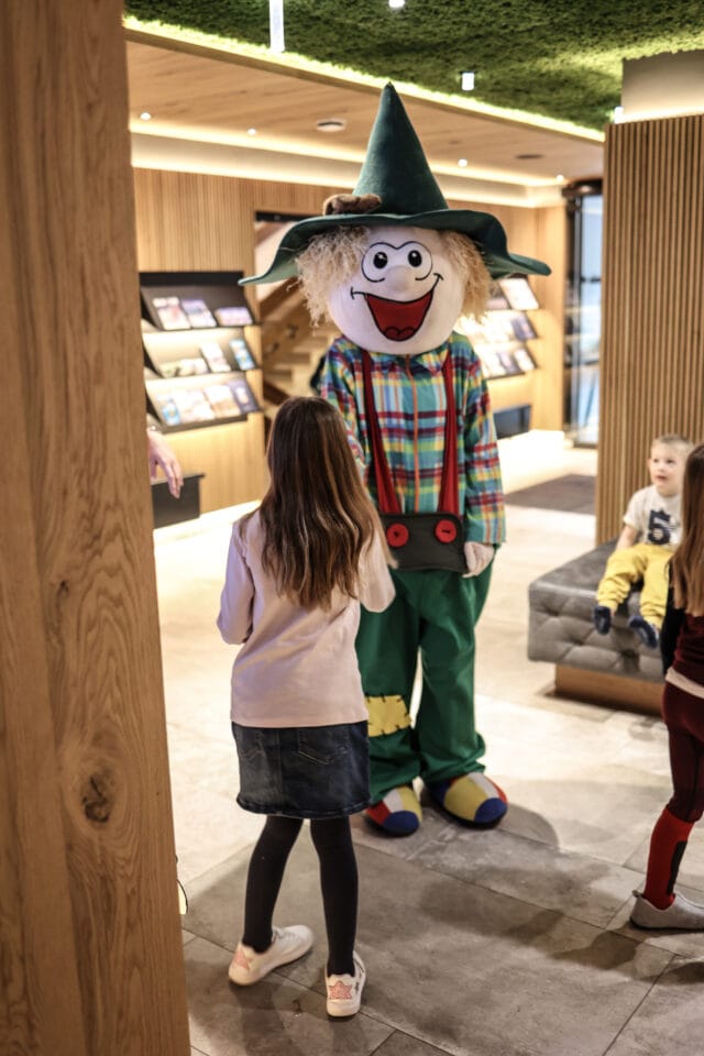 Kind spricht mit einem Maskottchen im Innenbereich