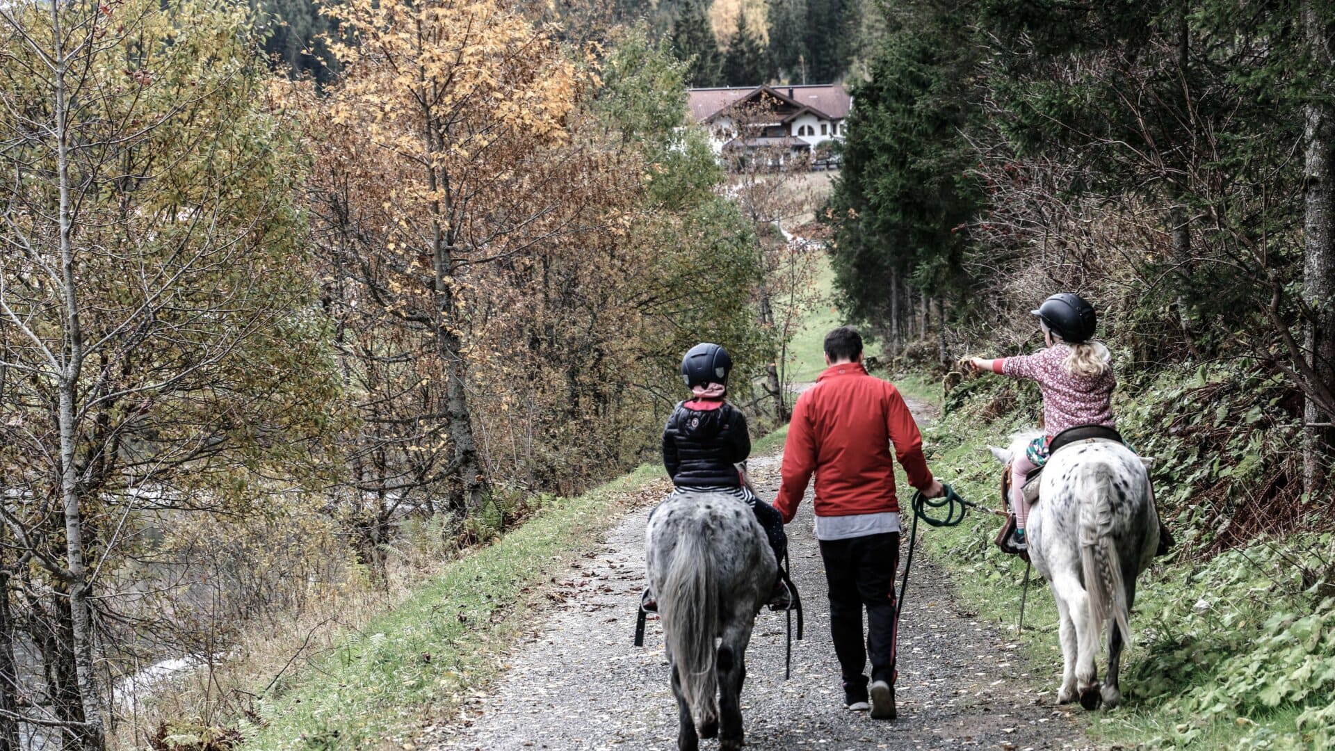 Familie reitet auf Pferden in der Natur.