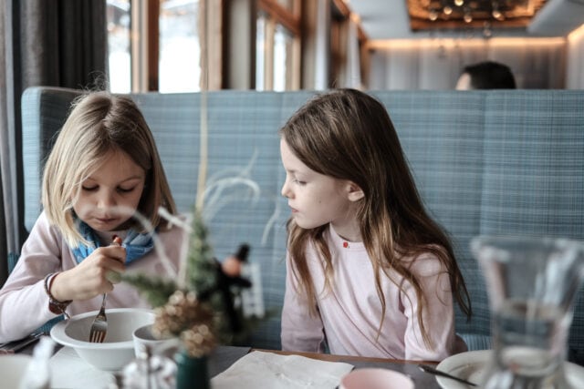 Zwei Mädchen sitzen am Tisch und essen.