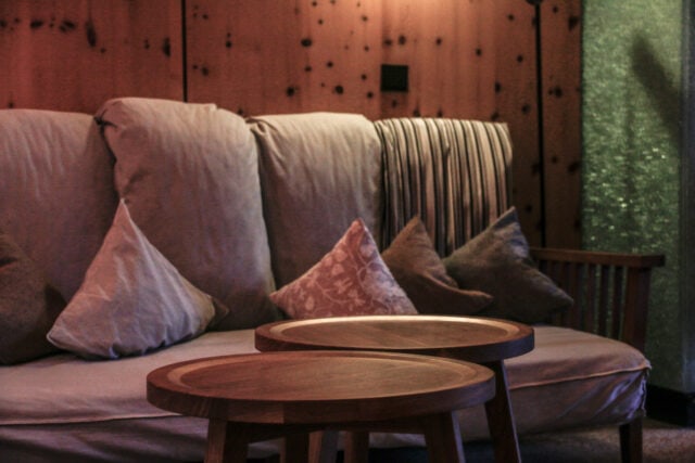 Gemütliche Sitzecke mit Kissen und Holztischen.