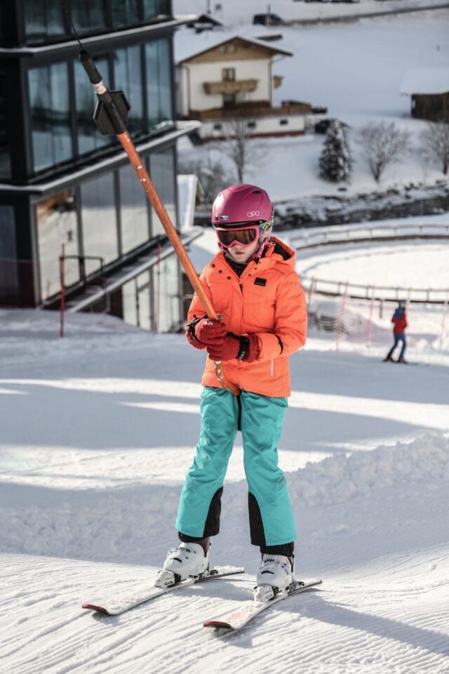 Kind steht auf Skiern in der Schneelandschaft
