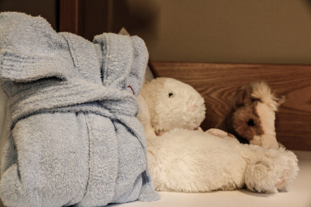 Blaue Bademantel und Kuscheltiere auf einem Tisch.