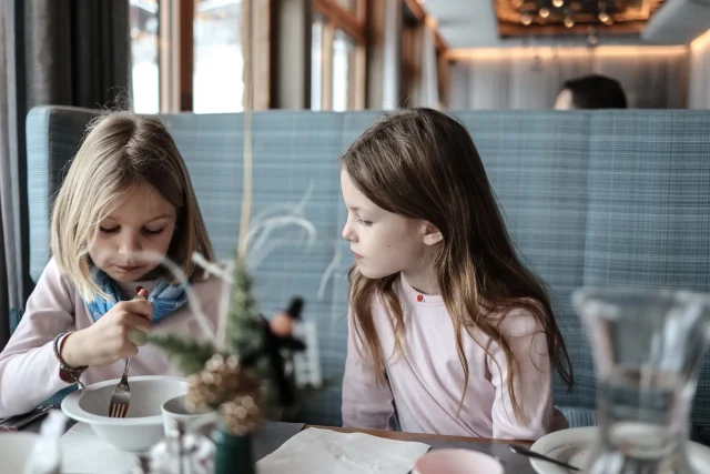 Zwei Mädchen sitzen am Tisch und essen.