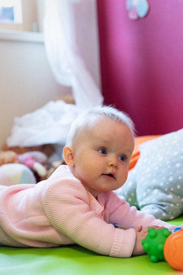 Baby krabbelt auf einer bunten Spielmatte.