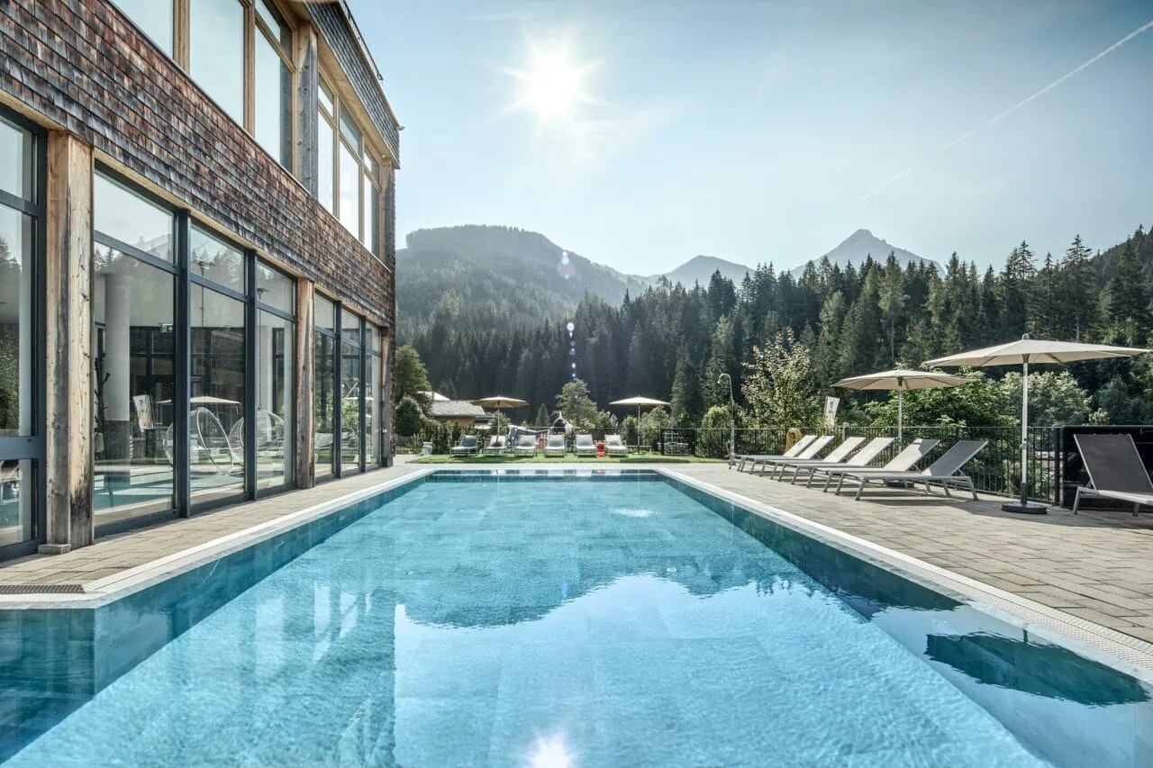 Schöner Pool mit Bergblick und Sonnenschirmen.