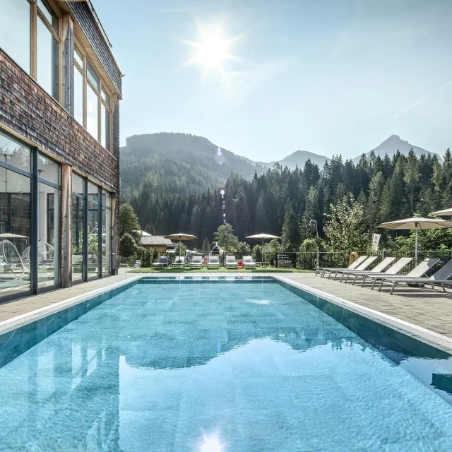 Schöner Pool mit Bergblick und Sonnenschirmen.