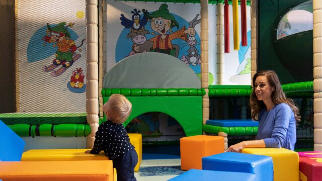Kind und Frau im Spielbereich mit bunten Blöcken.