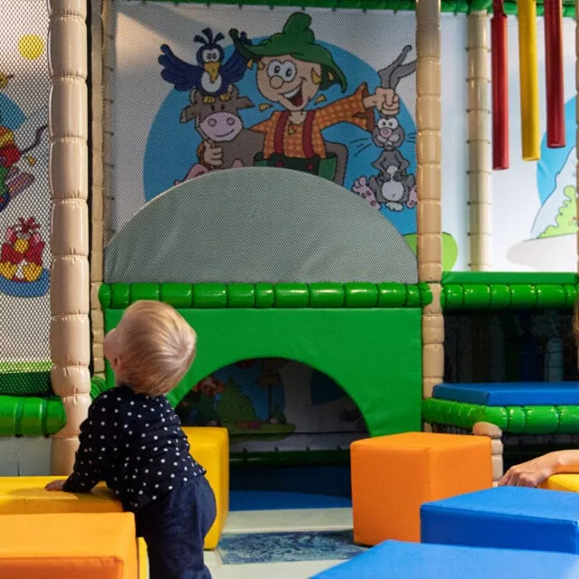 Kind und Frau im Spielbereich mit bunten Blöcken.