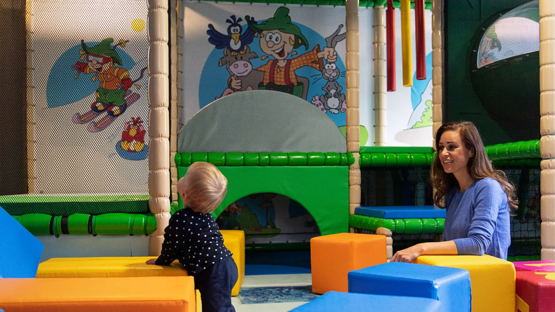 Kind und Frau im Spielbereich mit bunten Blöcken.