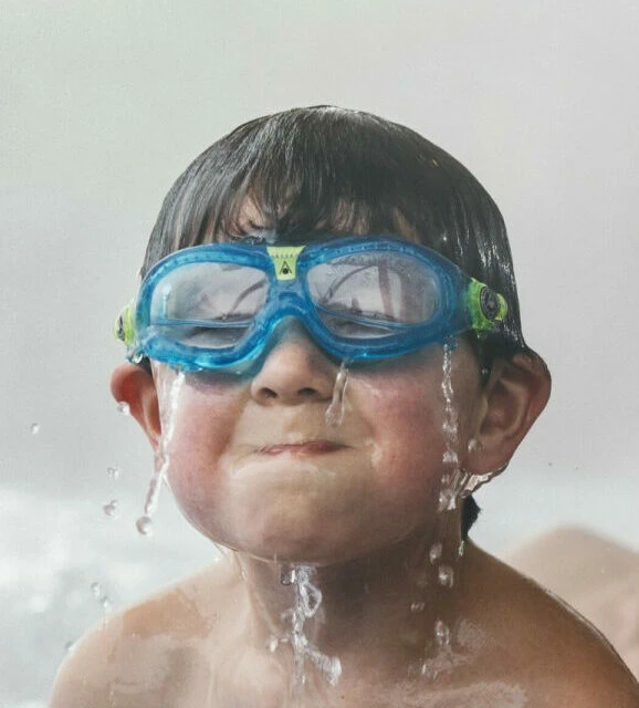 Junge mit Schwimmbrille und Wasserspritzern