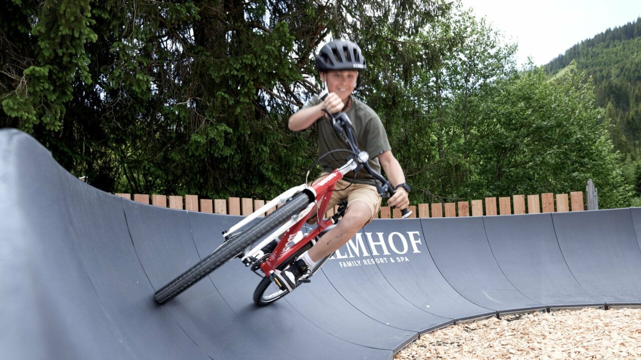 Junge fährt Fahrrad auf einer Wellenbahn.