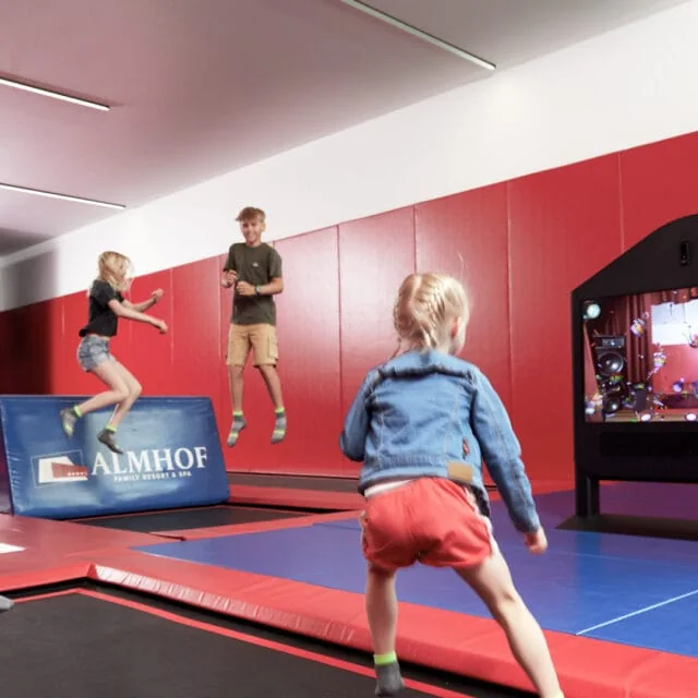 Kinder springen auf Trampolinen in einer Halle.