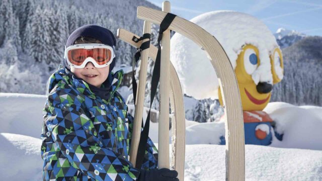 Junge mit Schlitten im verschneiten Winterwald