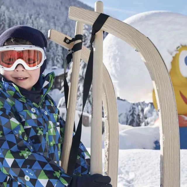 Junge mit Schlitten im verschneiten Winterwald