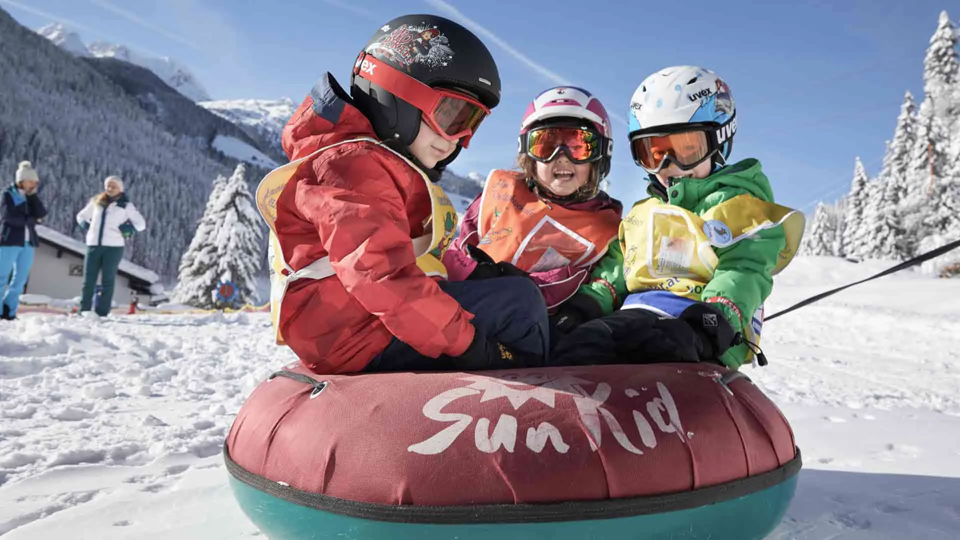 Drei Kinder beim Wintersport im Schnee.