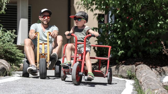 Vater und Sohn fahren auf Dreirädern.