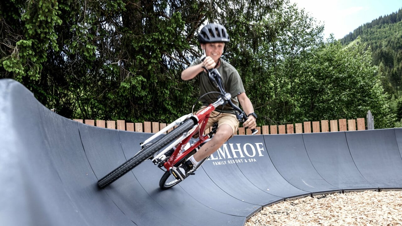 Junge fährt BMX auf einer Kurvenbahn.