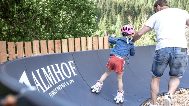Vater hilft Tochter beim Rollerskaten im Freien.