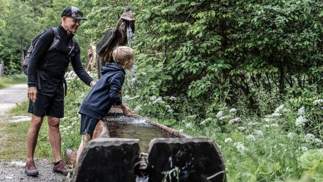 Mann und Kind an einem Wasserlauf im Wald