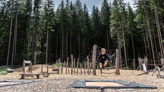 Kind spielt auf Spielplatz im Wald.