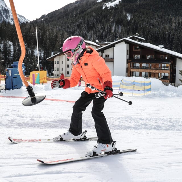 Skifahrendes Kind auf verschneiter Piste.