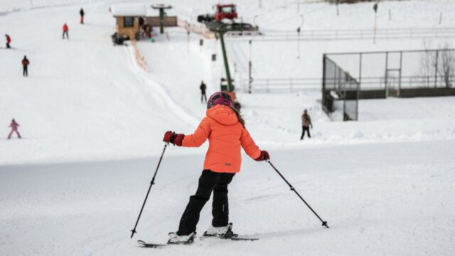 Kind fährt Ski im verschneiten Skiressort.