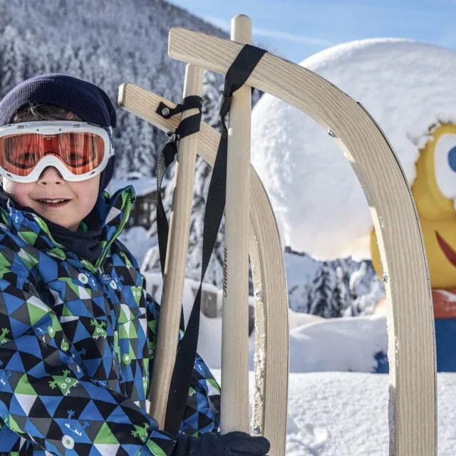 Junge mit Schlitten im Schnee vor Figurbild