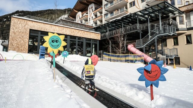 Kind fährt Ski in verschneiter Umgebung mit Blumen