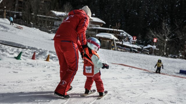 Kind lernt Skifahren mit einem Lehrer.