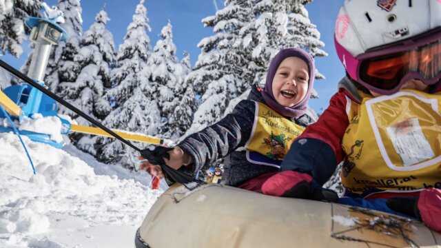Kinder beim Spiel im Schnee mit Schlitten.