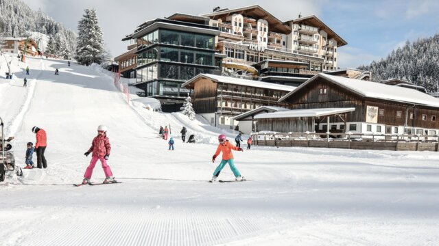 Kinder beim Skifahren in schneebedecktem Gebiet.