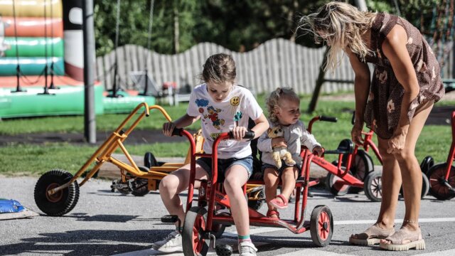 Kinder fahren mit Dreirädern auf dem Spielplatz.