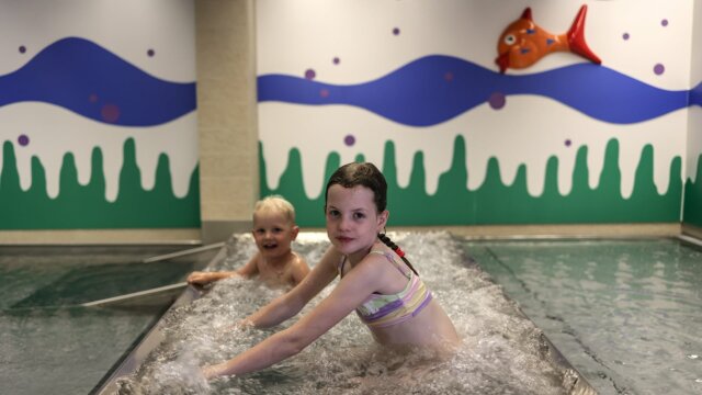 Kinder im Wasserbereich mit bunter Wandgestaltung.
