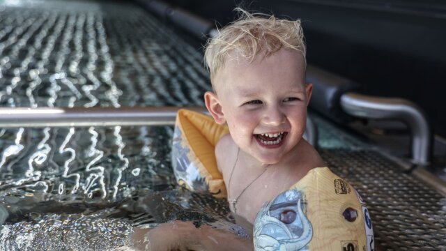 Fröhliches Kind im Wasser mit Schwimmflügeln.