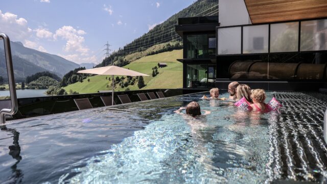 Familie im Infinity-Pool mit Bergblick