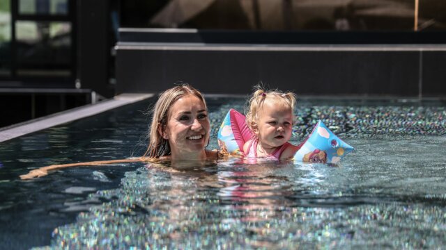 Frau und Kind im Wasser mit Schwimmhilfen