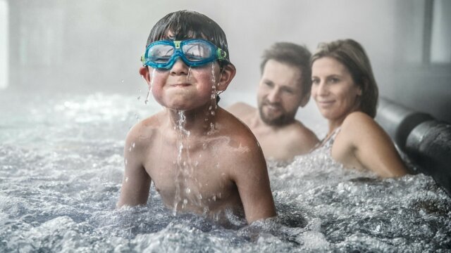 Junge mit Schwimmbrille im Wasser spritzt.