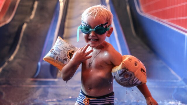 Lachendes Kind mit Schwimmhilfen im Wasser