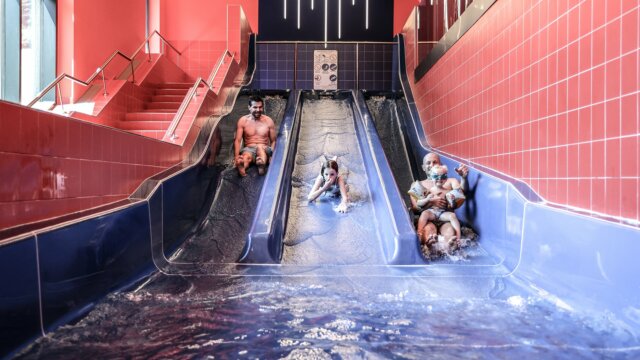 Familie rutscht begeistert die Wasserrutsche hinunter.