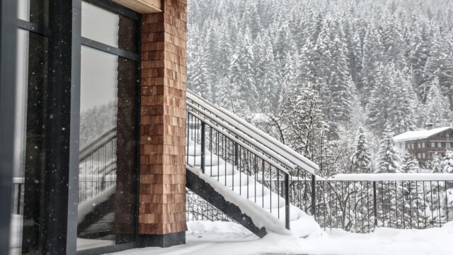 Schneebedeckte Treppe neben einem Fenster.