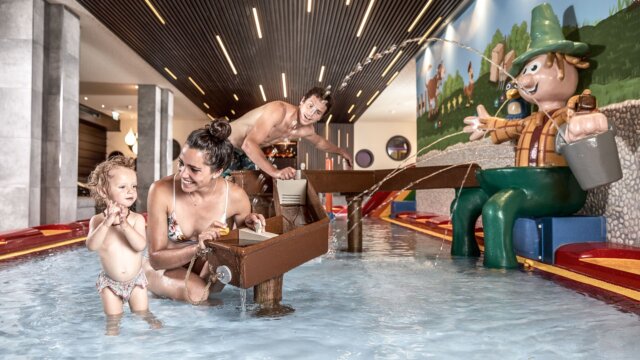 Familie beim Spielen mit Wasser im Erlebnisbad
