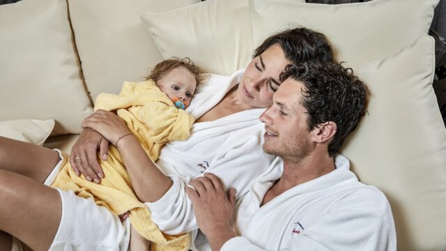 Familie entspannt zusammen auf dem Sofa.