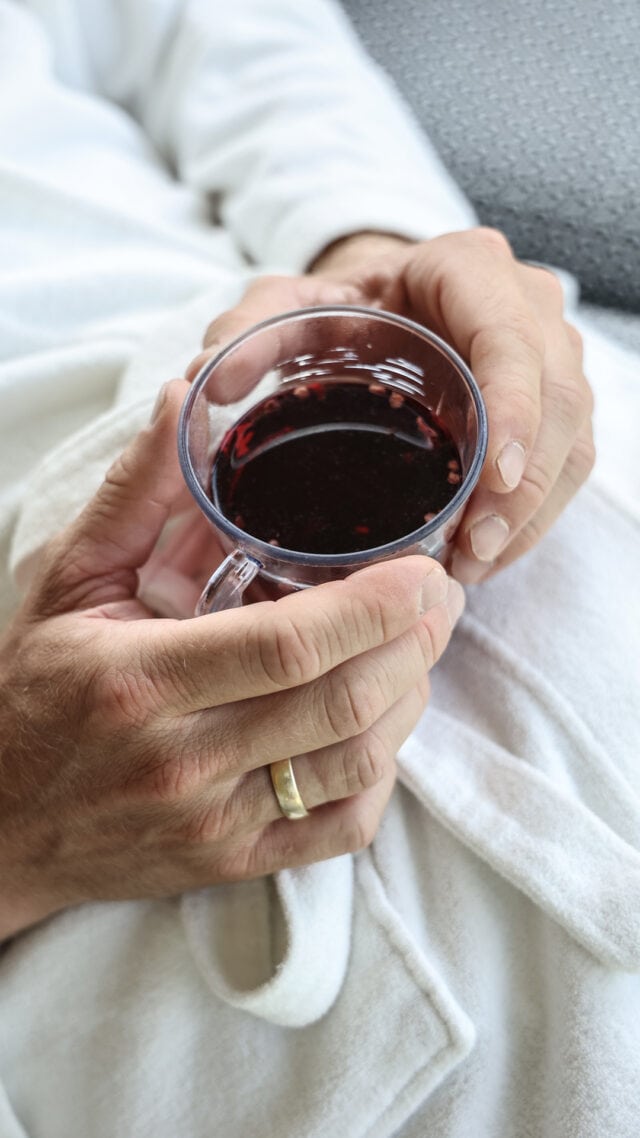 Eine Hand hält eine Tasse Rotwein.