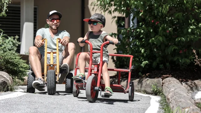 Vater und Sohn fahren auf Dreirädern.