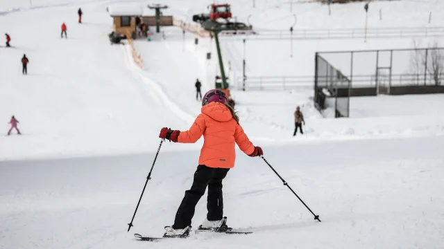 Kind fährt Ski im verschneiten Skiressort.