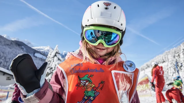 Mädchen in Skiausrüstung mit Helm und Sonnenbrille