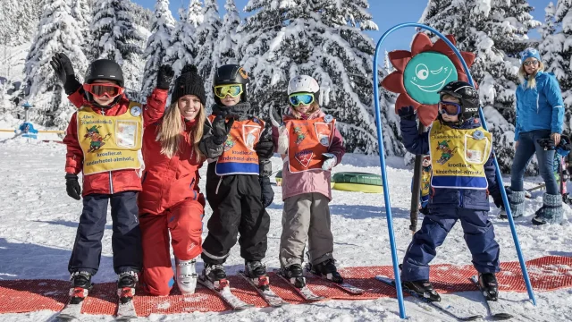 Kinder beim Skifahren mit einer Lehrerin im Schnee.