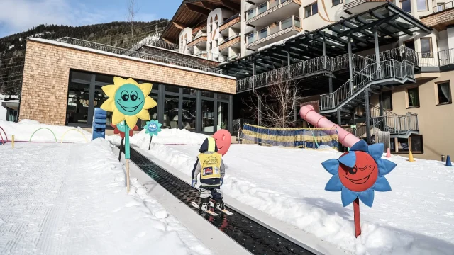 Kind fährt Ski in verschneiter Umgebung mit Blumen