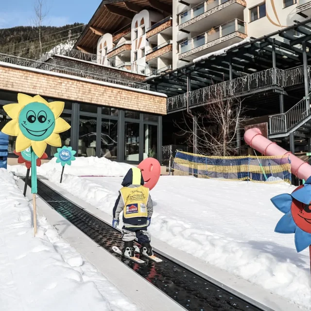 Kind fährt Ski in verschneiter Umgebung mit Blumen